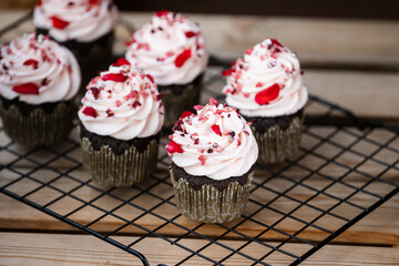 Dark chocolate cupcakes on black oven rack, decorated in valentine style