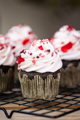 Dark chocolate cupcakes on black oven rack, decorated in valentine style