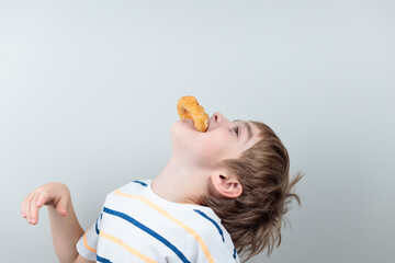 The boy greedily swallows donuts or crumpets, throwing back his head