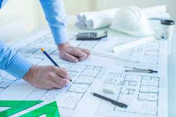 ARCHITECT OR DRAFTSMAN DRAWING PLANS OF THE FLOOR PROJECT OF A HOUSE IN THE STUDIO. SELF EMPLOYED CONCEPT. SELECTED FOCUS.
