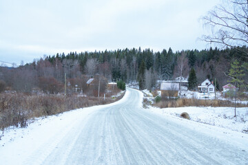 Landscape with a snow-covered road, rocks and forest. An empty winter highway in the forest.