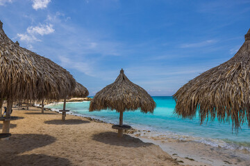 Beautiful view of sandy beach of Atlantic ocean with sun parasols. Aruba island.