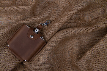 Hip flask in crazy horse leather case on burlap background. Banner with copy space for text place