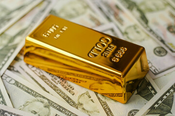 Gold bar on US dollar bill banknotes. Buying gold bars for investment.