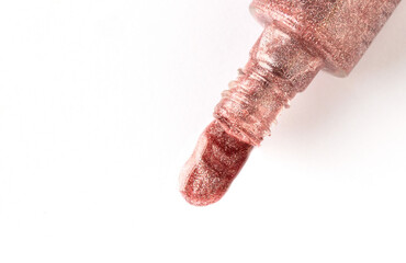 Glitter nail polish pouring from the nail bottle on white background, top view