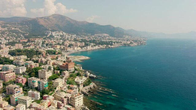 Panoramic View of old Mediterranean Town in Genoa, Italy, Europe. Coast of City with Ligurian Sea and coastal architecture of Boccadasse Place. Urban and European travel. 4k drone shot