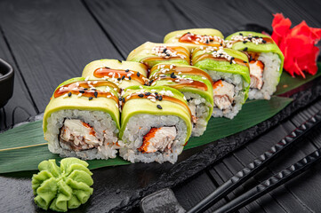 Sushi roll with smoked eel unagi covered by avocado and sesame seeds