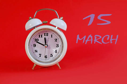  Calendar for March 15: a white alarm clock on a crimson background close-up, the numbers 15, the name of the month of March in English