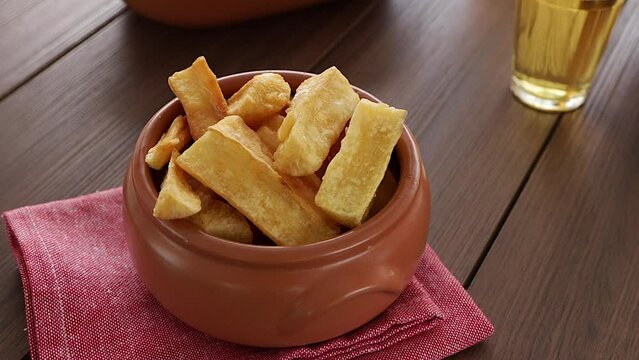 A portion of fried maniocs ( Mandiocas ) on a wooden table, traditional brazilian food.