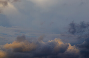 cloud at sunset illuminated by the rays of the sun against a gray stormy sky