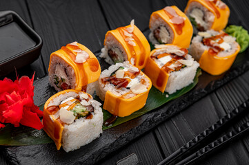 Traditional delicious fresh sushi roll set on a black background . Sushi roll with rice, cream cheese, salmon.