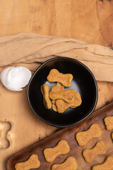 Homemade healthy dog treats on rustic wooden table with cookie cutter, eggshell and cloth.