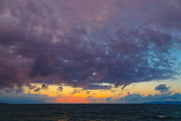 Dark blue sea and purple clouds in setting sun have a rich color scheme.