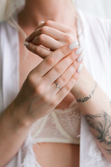 Morning preparations of a beautiful, sexy bride with a wedding bouquet in lingerie, a bathrobe in a hotel, where she puts on shoes in a wedding dress