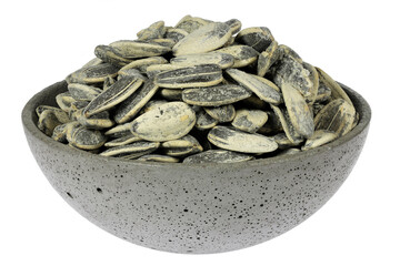 whole roasted and salted sunflower seeds in a concrete bowl isolated on white background