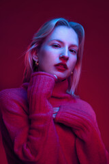 Portrait of a serious young blond woman isolated on magenta background. Viva magenta.