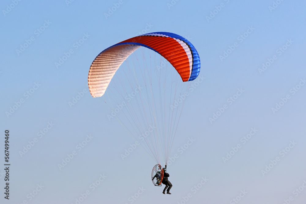 Poster paramotor pilot flying in a blue sky