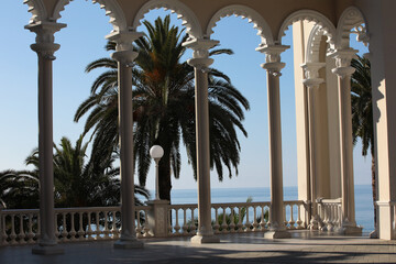 White baroque balcony on the seafront with a palm tree