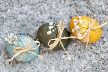 Fototapeta na wymiar Baby blue, dark grey and yellow Easter eggs with spring flowers. Festive decoration.
