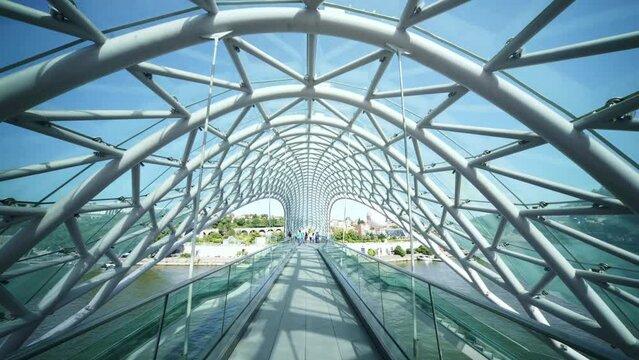 Bridge of Peace, pedestrian bridge over Kura River in Tbilisi, capital of Georgia. Built with steel, blue glass, modern design. 