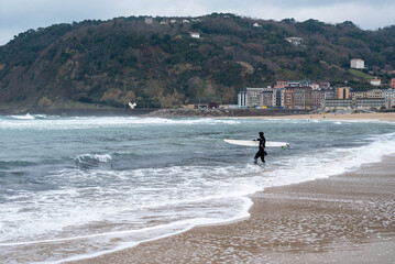 a surfer getting into the sea to surf on a winter afternoon