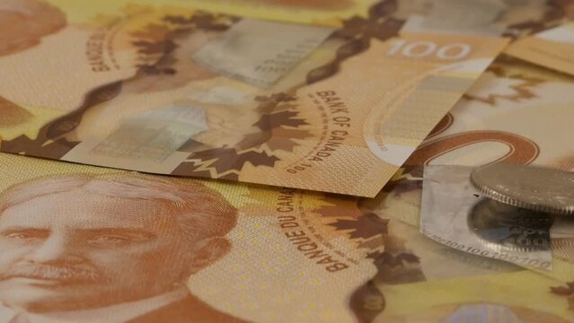 Falling Canadian coins on 100 dollar polymer banknotes with a portrait of Robert Borden. Slow motion.
