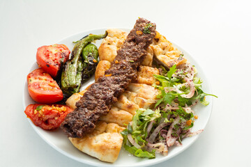 Grilled Adana Kebab meat with vegetables and pide. Adana Kebap on white background.