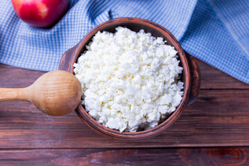 dairy product cottage cheese in a plate with a glass of milk and apples on a wooden background