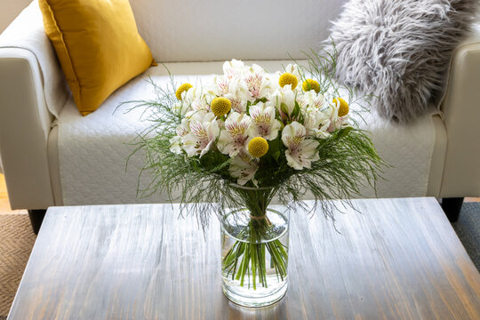 Craspedia and alstroemeria flowers in a vase on a coffee table