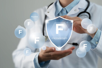 Microelement supplement concept. Shield in doctor`s hands with Fluorine icon.