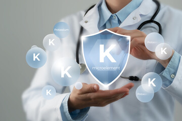 Microelement supplement concept. Shield in doctor`s hands with Potassium (K) icon.