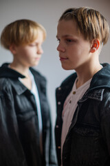 Two happy boys, happy brothers who are seriosly happily together. Brothers stay on grey background. modern tenagers.book cover. one boy in focus other out of focus