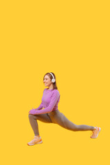 Vertical photo of a young woman performing lunges while listening to the music.