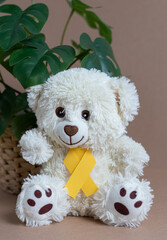Toy bear with a yellow ribbon on a nude background.