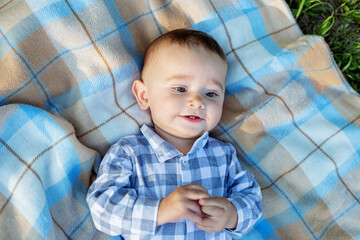 Cute little baby lying on blanket and smiling, top view. Concept of childhood and newborn baby care