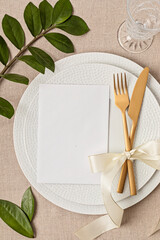 Festive wedding, birthday table setting with golden cutlery and porcelain plate. Blank card mockup....