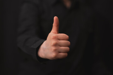 man raising thumb up in approval, image with black background