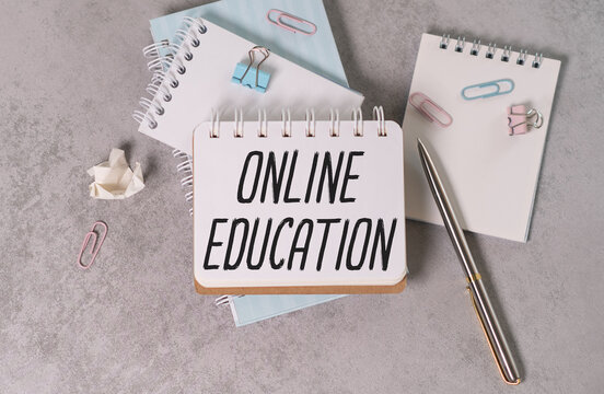 Online Education text on a notebook with a pen and a paper clip on a gray background.