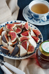 Plate with whey cheese and fresh figs and a blue and white cup of green tea	