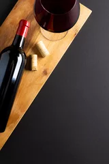  Bottle of red wine, glass and corks on black background, with copy space © vectorfusionart