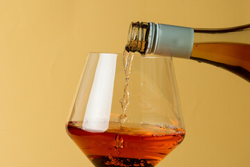 Bottle of rose wine and glass on yellow background, with copy space