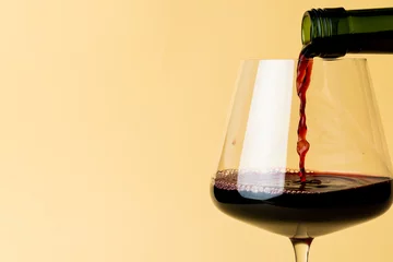 Fotobehang Bottle of red wine and glass on yellow background, with copy space © vectorfusionart