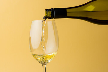 Bottle of white wine and glass on yellow background, with copy space