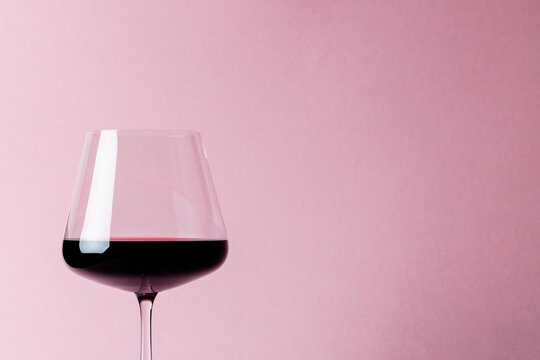 Glass of red wine on pink background, with copy space