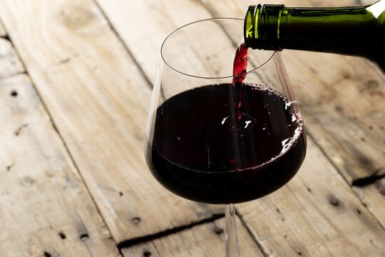 Bottle of red wine and glass on wooden background, with copy space