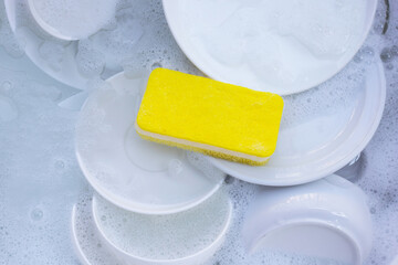 Dishes and bowls in water and bubbles of dishwashing liquid