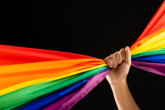 Hand Holding Rainbow Coloured Flag With Copy Space On Black Background