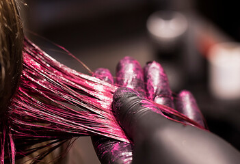 close-up coloring a strand of blond hair in a bright pink color, beauty salon