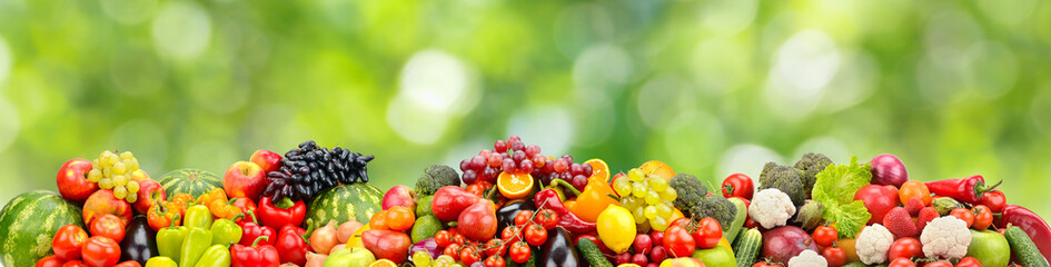 Multi-colored berries, fruits and vegetables on green blurred