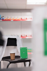 Greenscreen chroma key mock up pills packages standing vertically on chair in pharmacy, empty drugstore filled with pharmaceutical products and supplements. Health care service support and concept